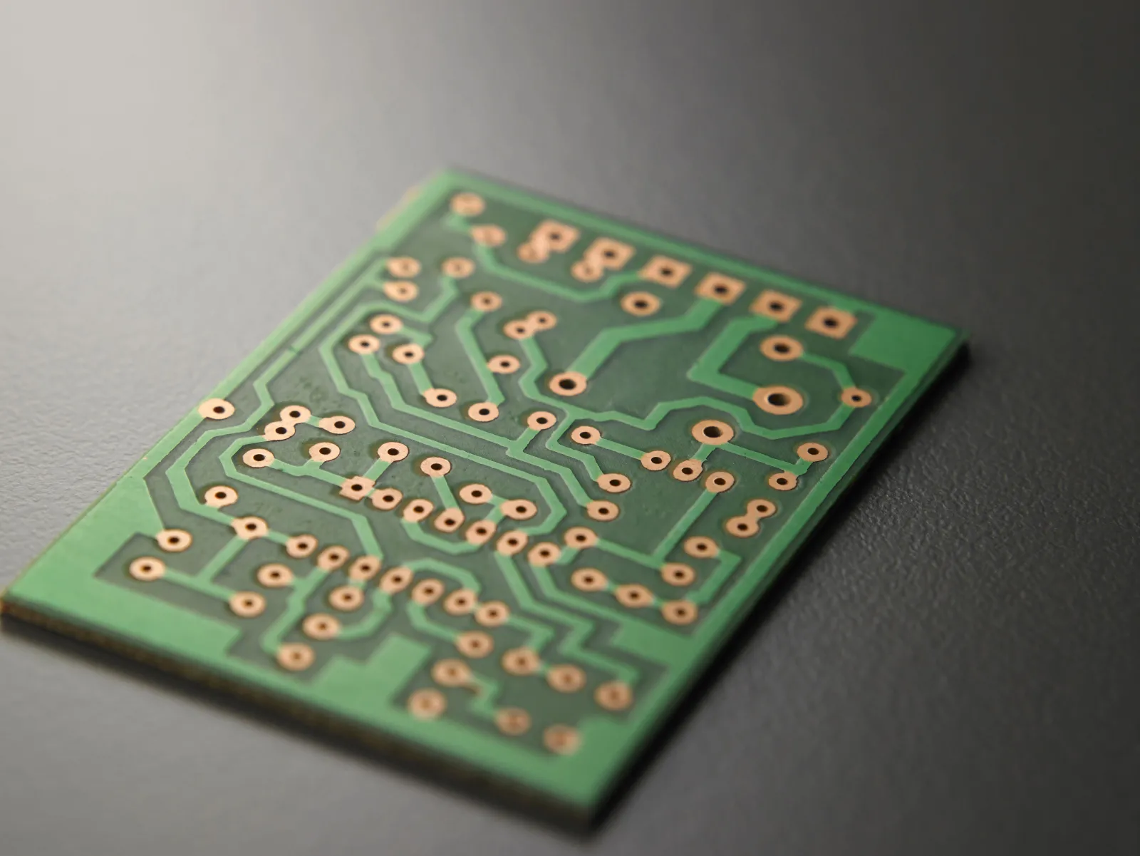 Close-up of a single-sided green PCB with copper trace routing for consumer electronics